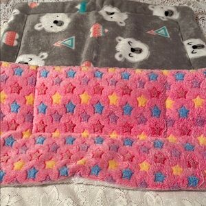 Two small puppy pads. One pink with stars and the other is gray with bears.
